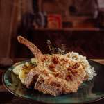 Kotlet schabowy* z kością po polsku, smażony na wędzonej słoninie*, ziemniaki*, młoda kapusta zasmażana*